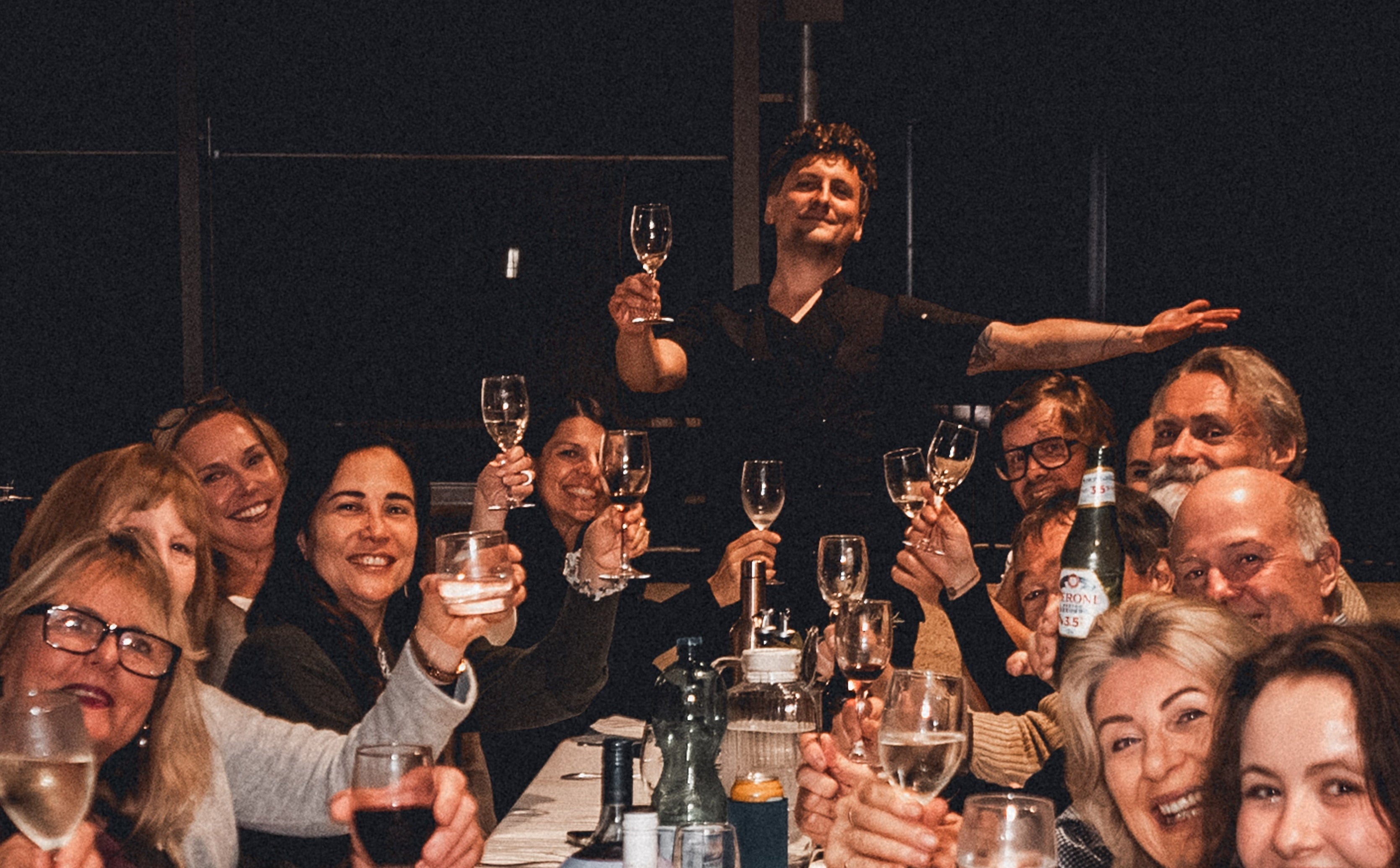Group of people enjoying a meal and drinks together at a long table.